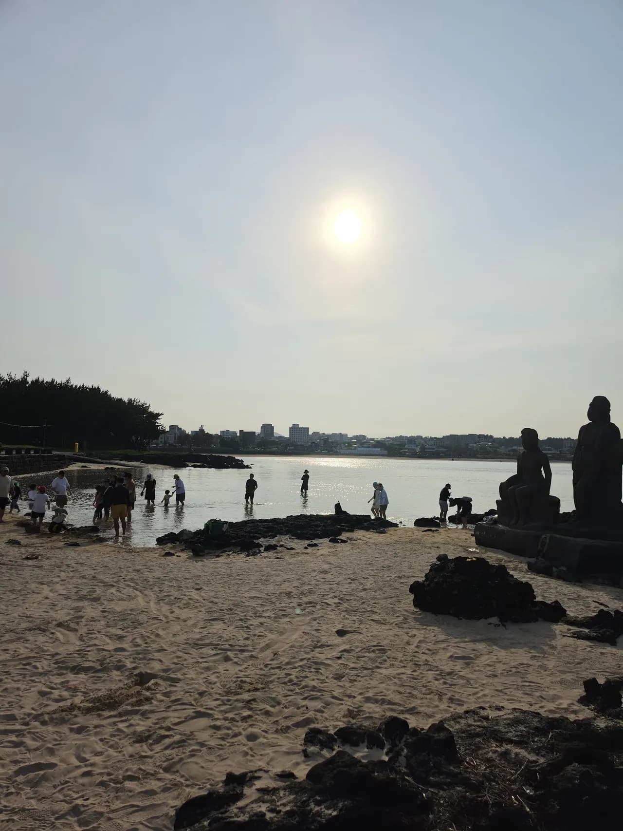 Sunset over the sea as figures wander the rocky shore at dusk