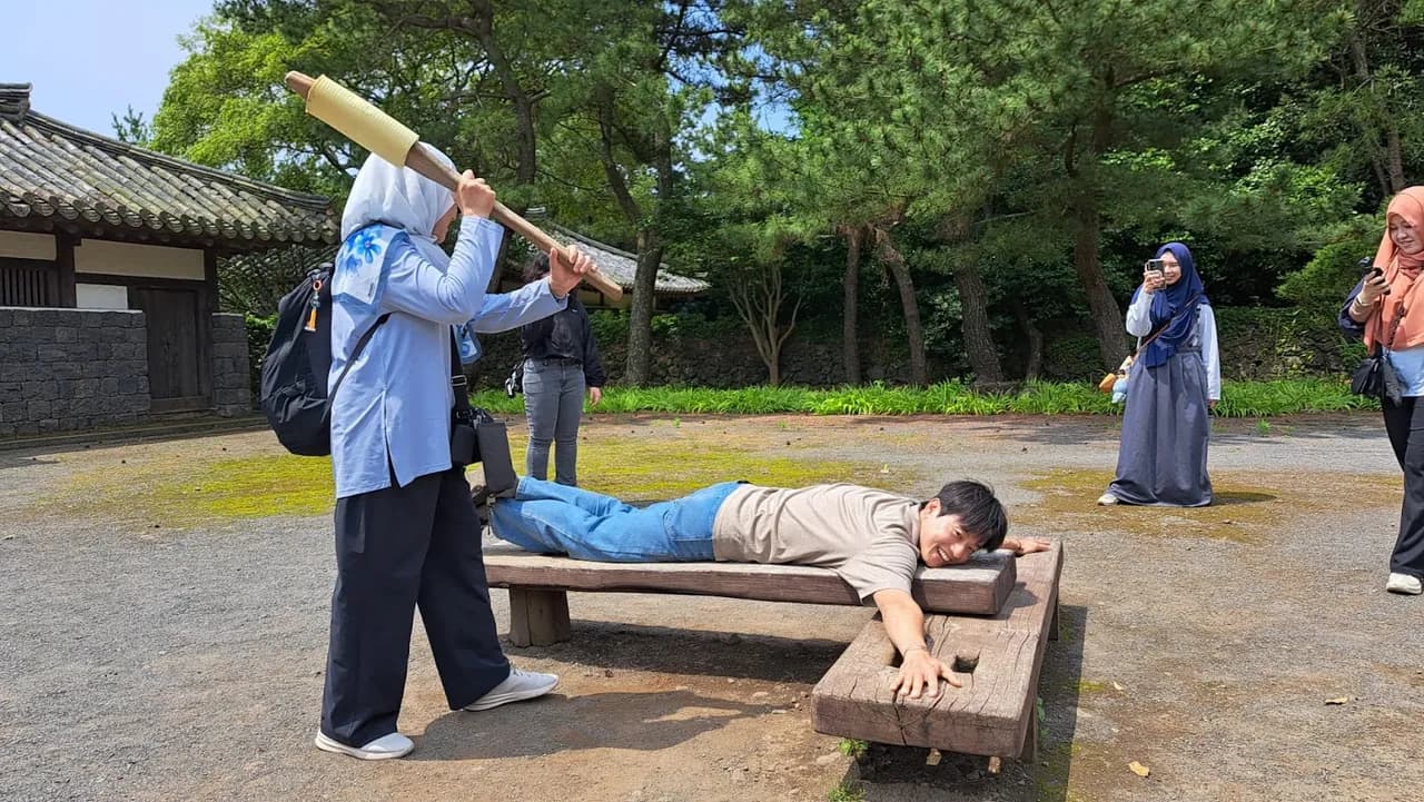 Trying out a Joseon-era punishment-bench photo op at the folk village