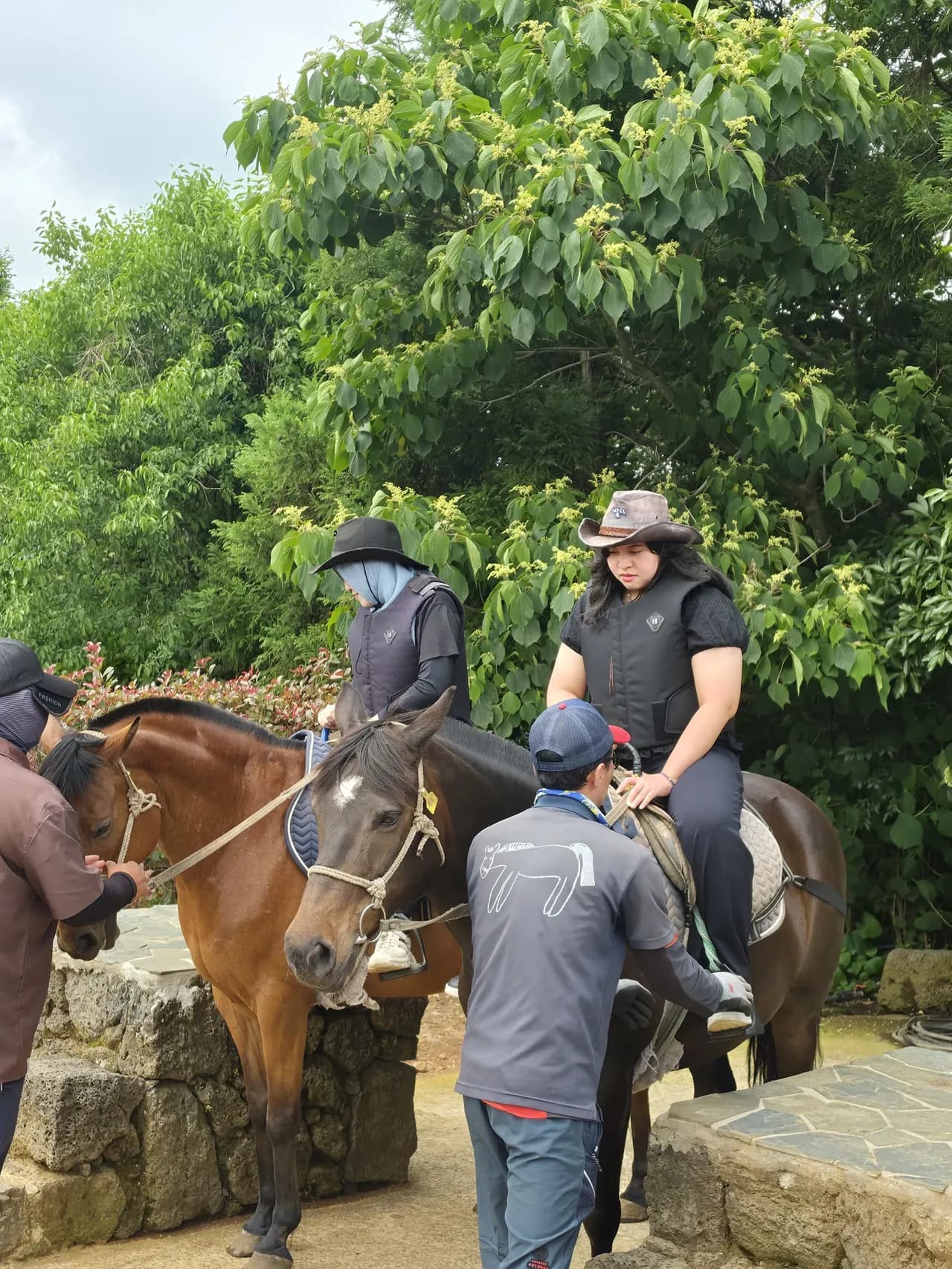 A guide helping a guest mount a brown horse