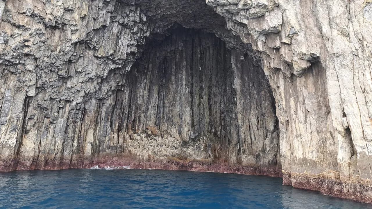 A columnar-basalt sea cave seen from the water