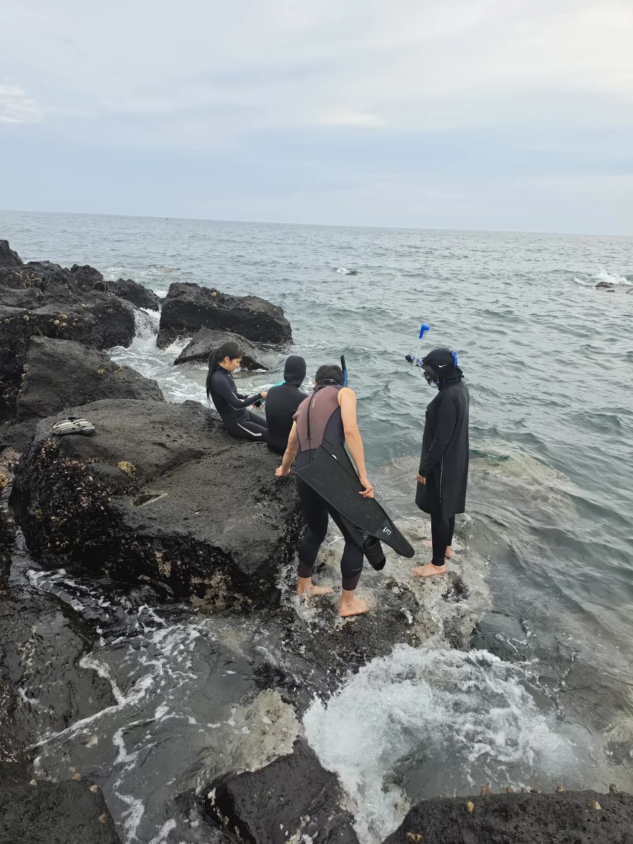 Wading across the black basalt tidal rocks along the Seongsan coast